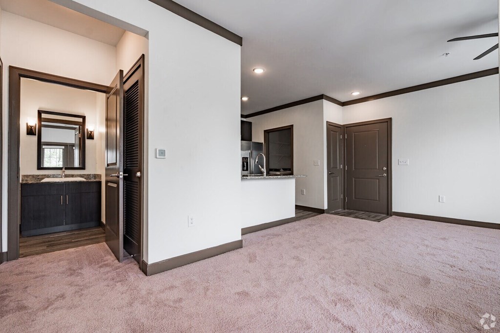 A room with a carpeted floor and a white wall with a brown door. at Century Belmont Station, Louisville, 40243