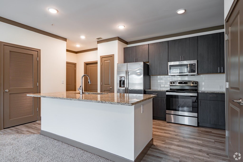 A modern kitchen with a white island and stainless steel appliances. at Century Belmont Station, Louisville, 40243