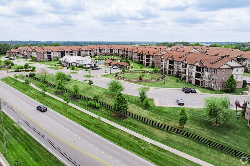 A road with cars and a grassy area with trees and apartment buildings in the background. at Century Belmont Station, Louisville, Kentucky