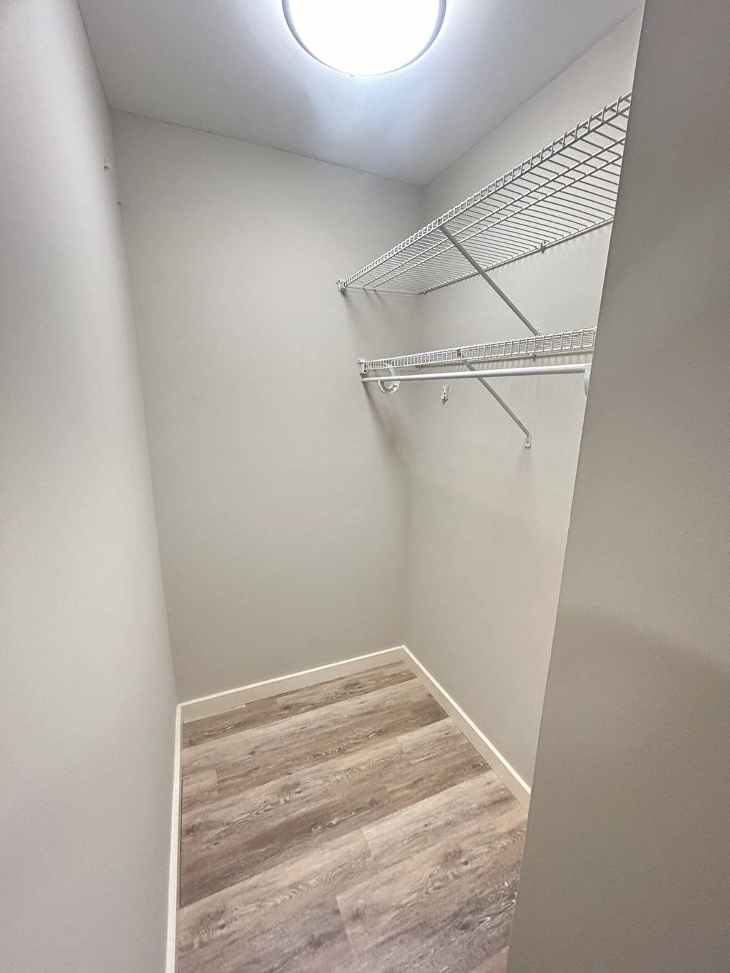 a walk in closet with a white wall and wood flooring at Briarcliff at Quechee Apartments, Quechee, Vermont
