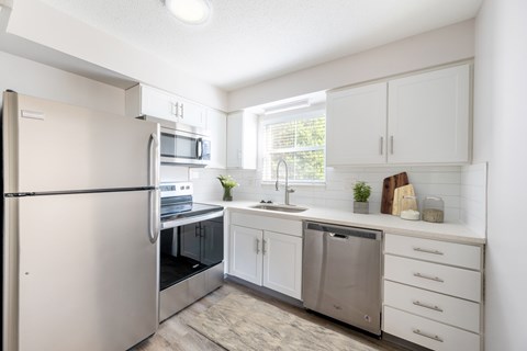 A modern kitchen with white cabinets and stainless steel appliances.