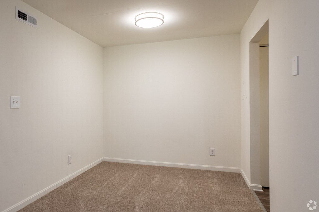a bedroom with white walls and carpet