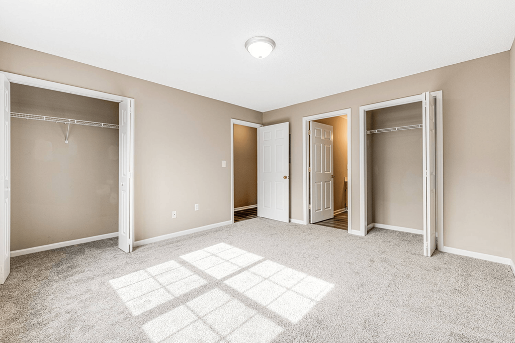 a bedroom with three closets and a carpeted floor and doors to three clos