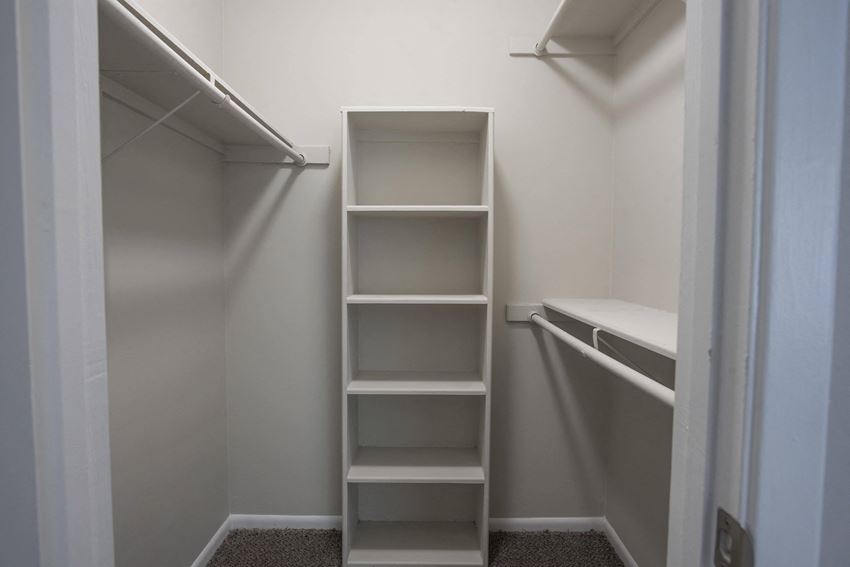 a walk in closet with empty shelves in a small closet