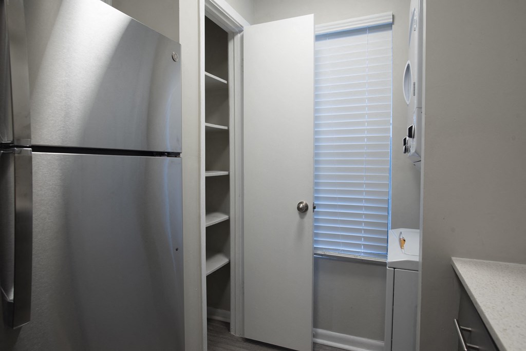 a kitchen with a refrigerator and a closet with shelves