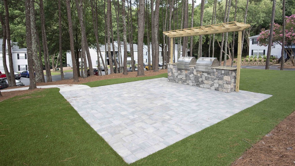a stone patio with a stone fireplace and a pergola