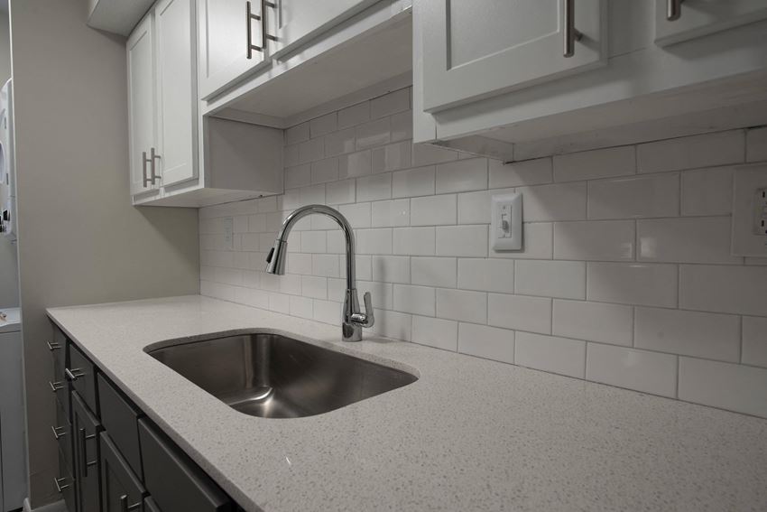 an empty kitchen with a sink and white cabinets