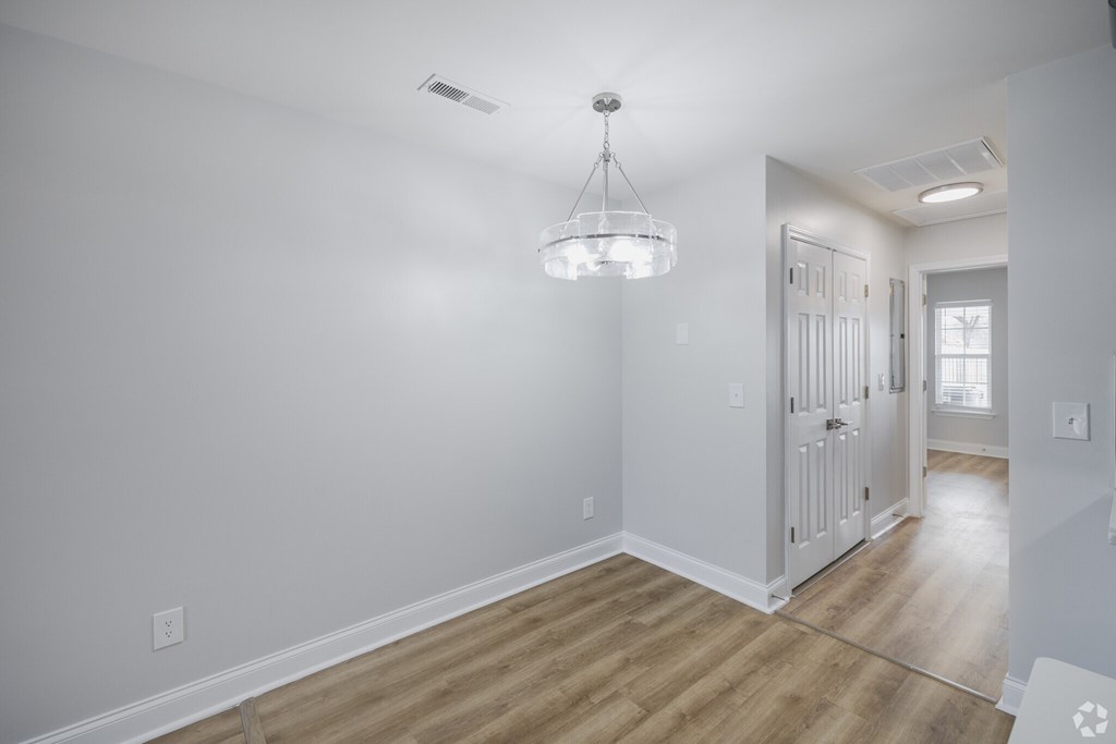 A room with a wooden floor and a chandelier hanging from the ceiling.
