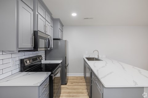 A kitchen with a black refrigerator and a white counter top.