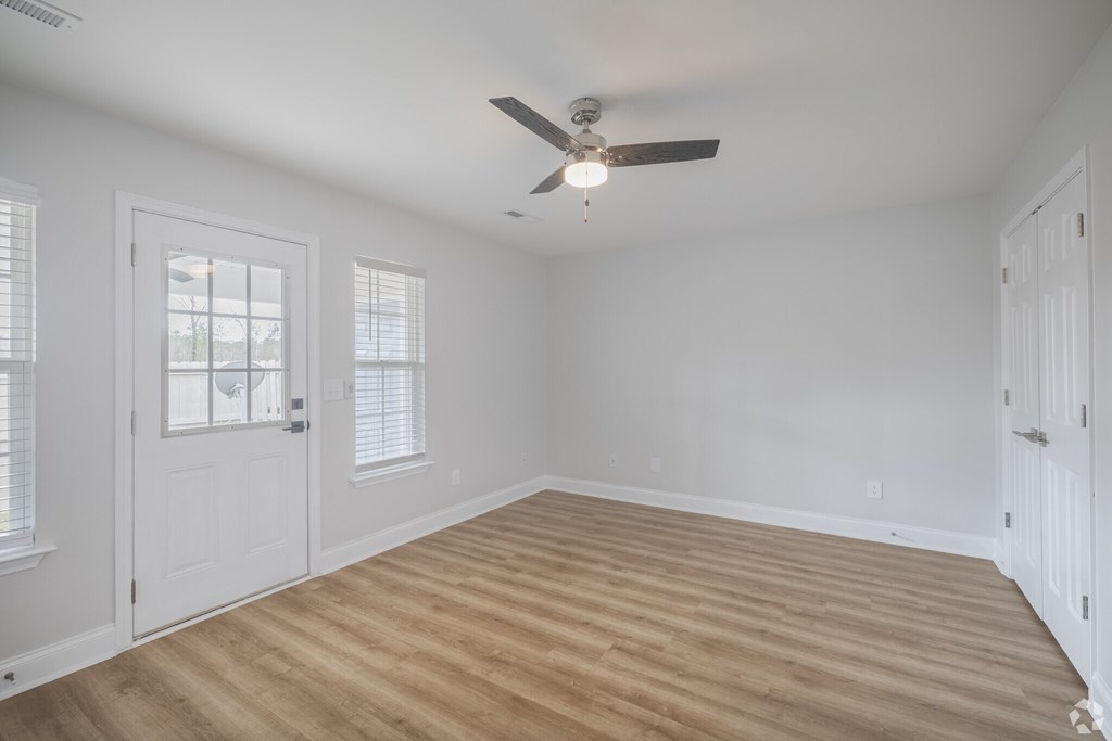 A room with a ceiling fan and wooden flooring.