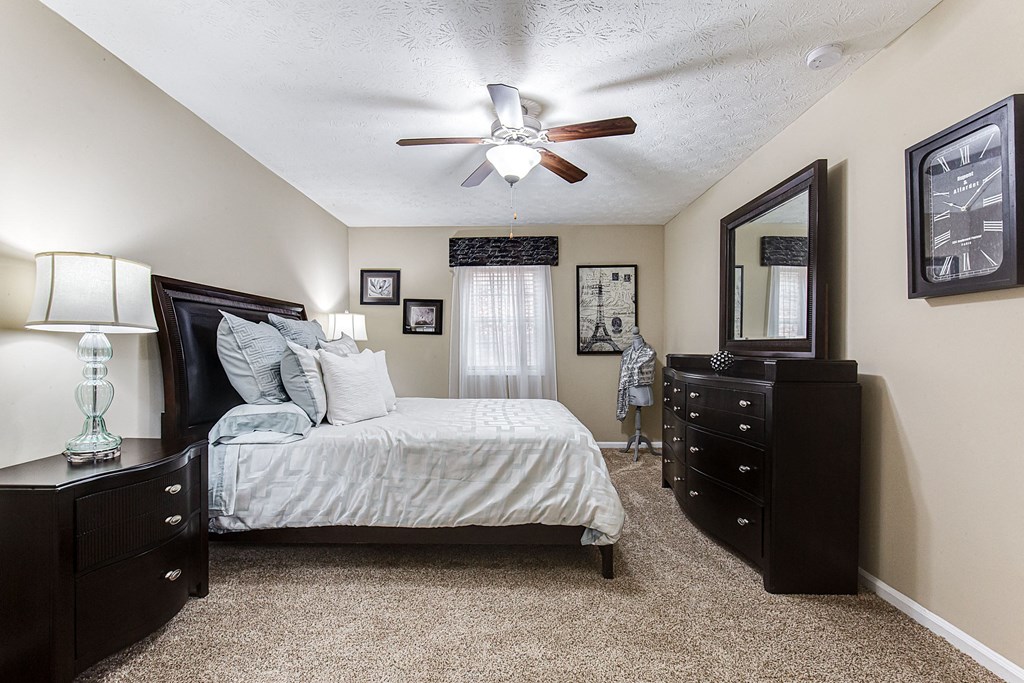 an empty bedroom with a bed and a ceiling fan