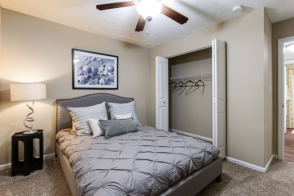 a bedroom with a bed and closet with a ceiling fan