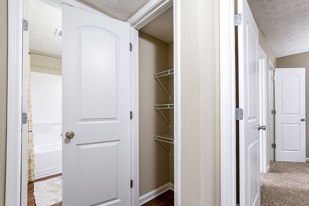 a walk in closet with a white door and a closet with shelves