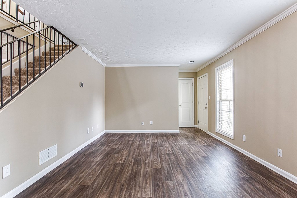an empty living room with wood flooring and a staircase