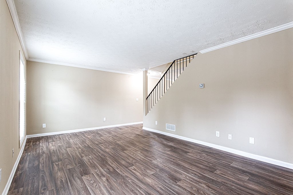 an empty living room with wood flooring and a staircase