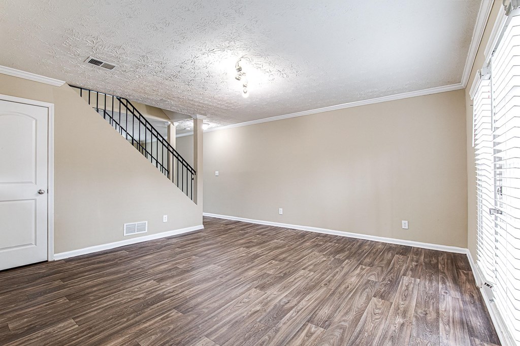 an empty living room with wood flooring and a staircase