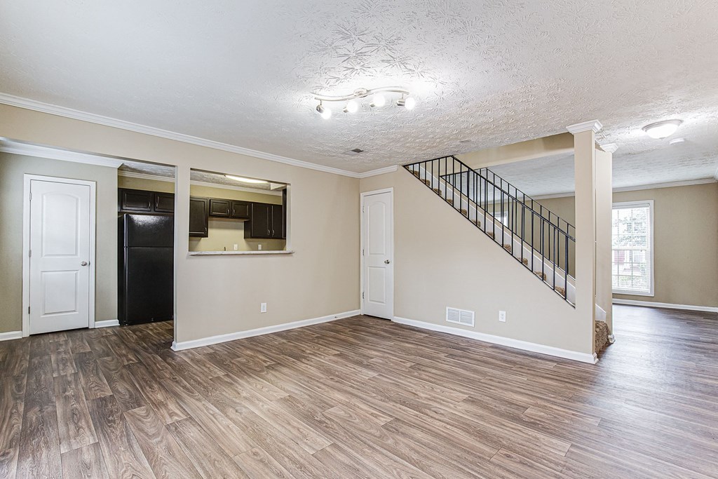 an empty living room with wood floors and a staircase