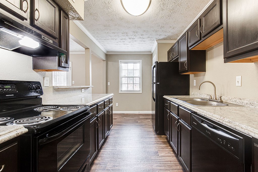 an empty kitchen with black appliances and counter tops