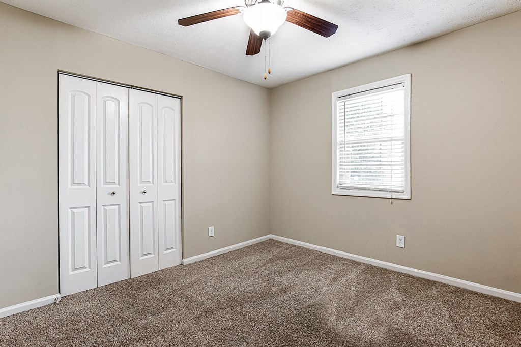 an empty room with carpet and a ceiling fan