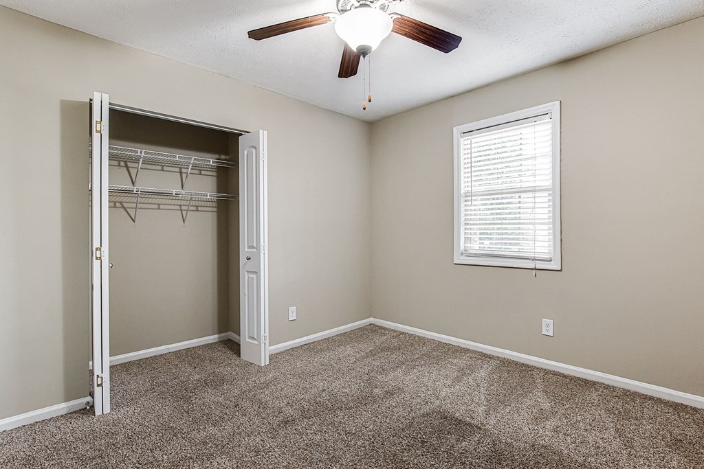 an empty bedroom with a closet and a ceiling fan