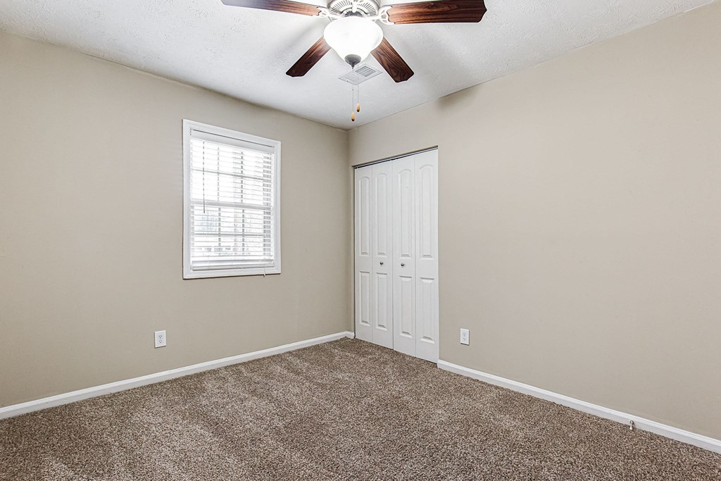an empty bedroom with a ceiling fan and a closet