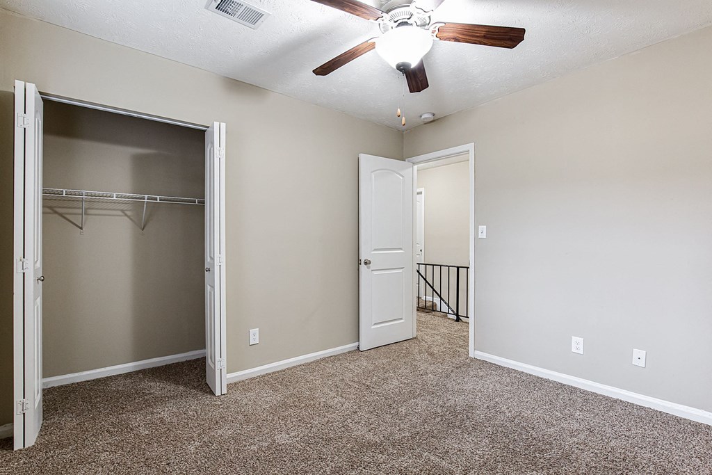 an empty bedroom with a closet and a ceiling fan