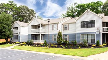 an apartment building with blue and white siding and a lawn