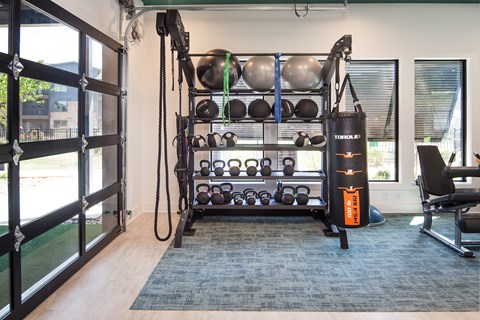 A resident fitness center with a weight rack, dumbbells, and a TRX suspension trainer.