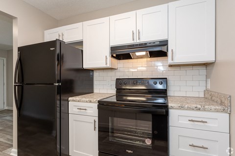 an updated kitchen with black appliances and white cabinets
