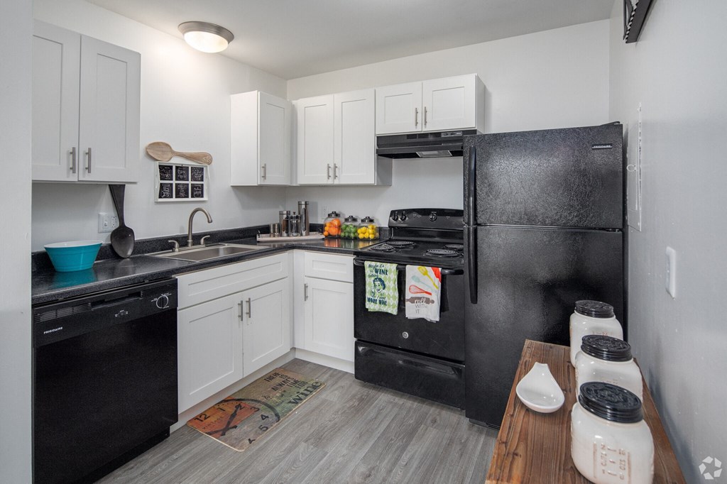 a kitchen with white cabinets and black appliances