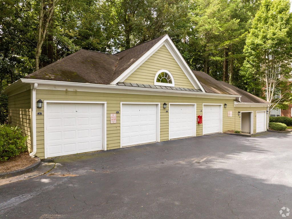 a yellow garage with two white doors and a driveway at Flats at North Springs, Sandy Springs