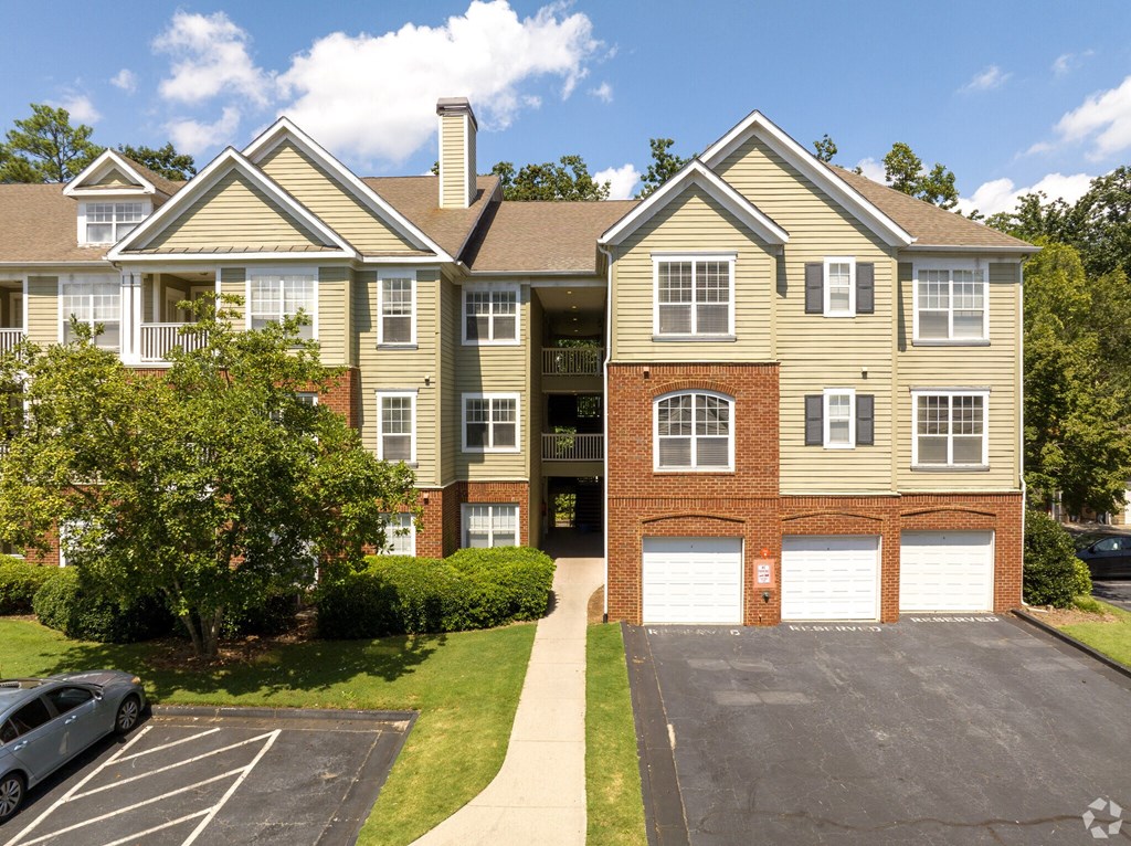 a two story apartment building with two cars parked in a driveway  at Flats at North Springs, Georgia