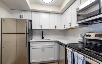 a kitchen with white cabinets and stainless steel appliances at The Essex, Florida, 32701