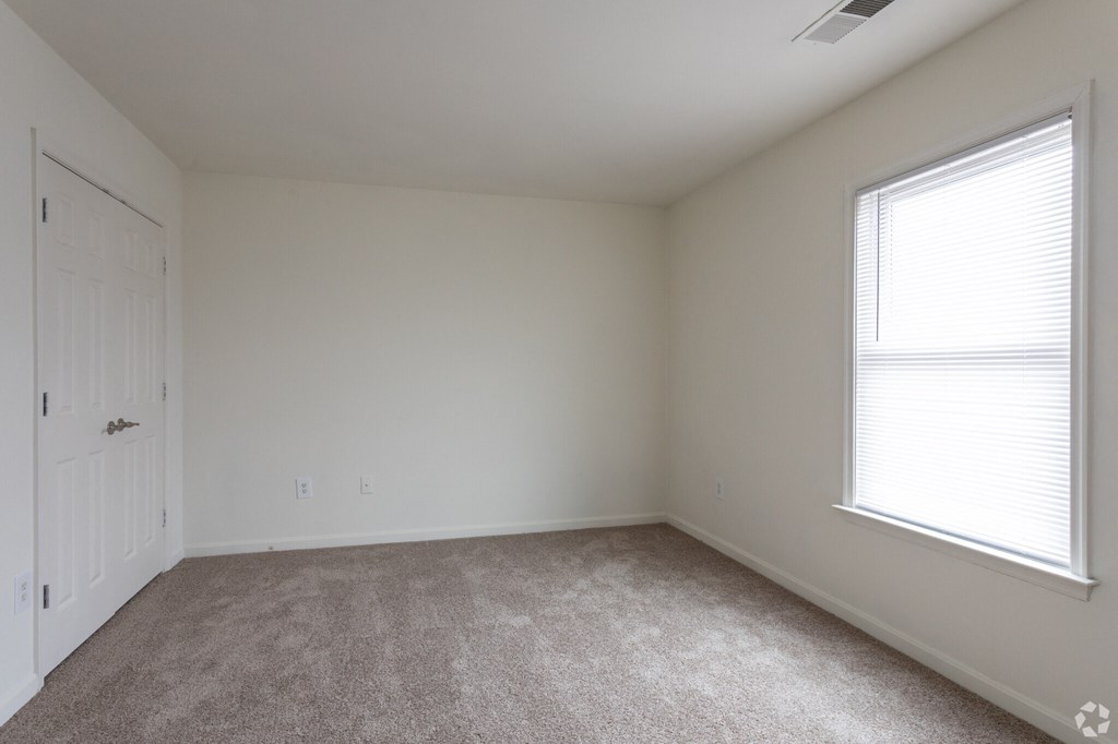 a bedroom with white walls and carpet