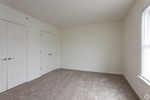 a bedroom with white walls and carpet and two doors
