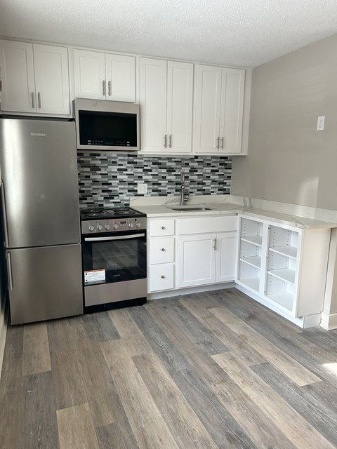 A kitchen with a stainless steel refrigerator, oven, and microwave at Briarcliff at Quechee Apartments, Quechee, 05059