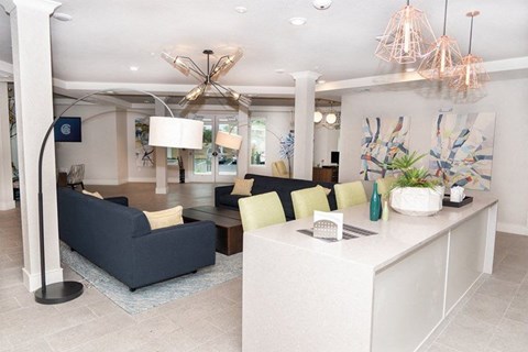 A modern living room with a dark blue sofa and a white kitchen island.