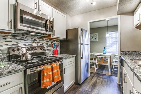 A kitchen with a black stove top oven and a black microwave above it.