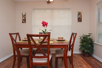 a dining room with a table and chairs and a red flower