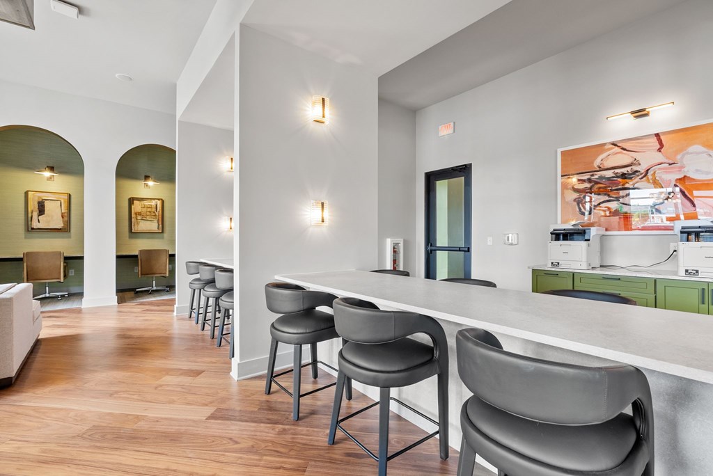 A white bar with grey chairs in a room with wooden floors.