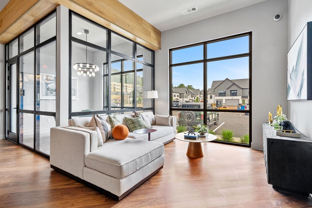 A modern living room with a large sofa and a view of the outside.
