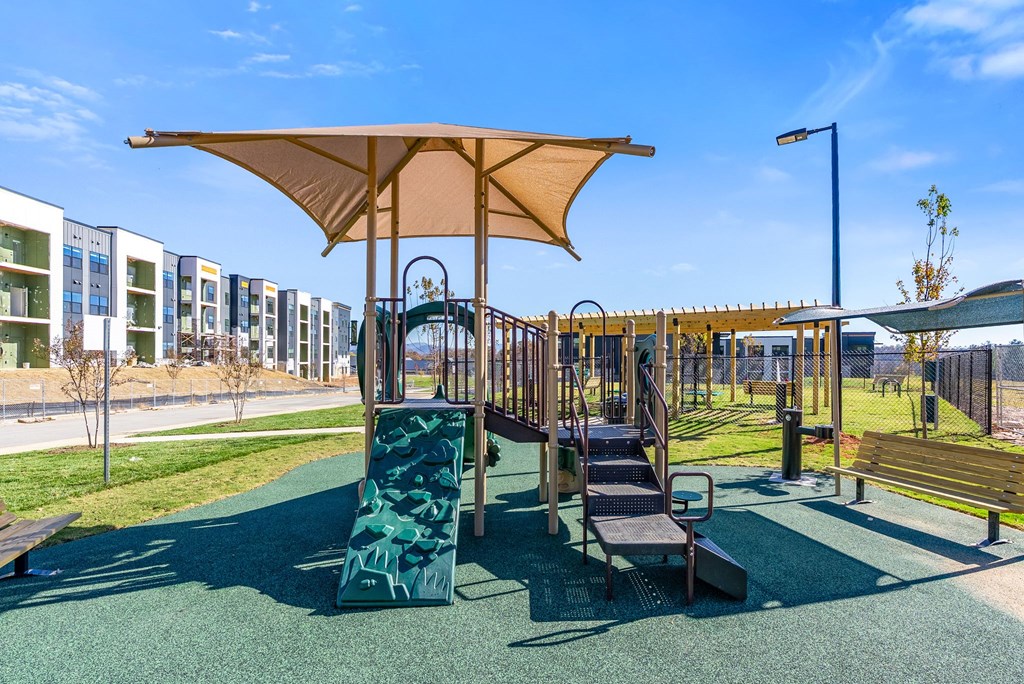 A playground with a green slide and a brown canopy.