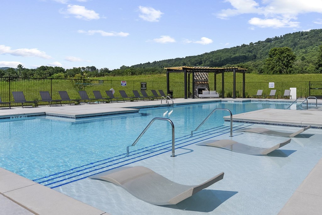 A large outdoor swimming pool with sun loungers and a pergola.