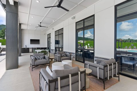 A modern living room with grey couches and a ceiling fan.