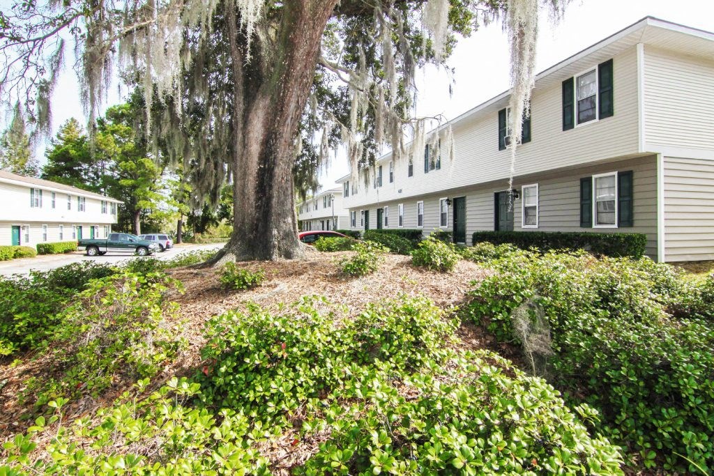 Exterior of apartments with trees at Lakewood Lodge in Hanahan, SC