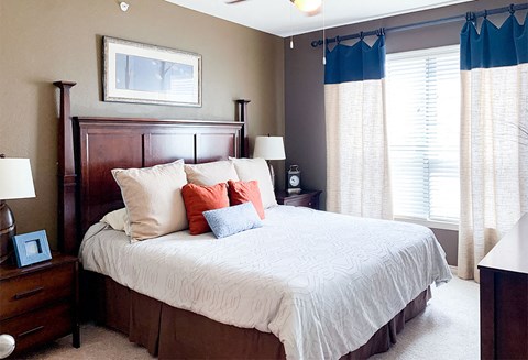 a bedroom with a large bed and two windows
