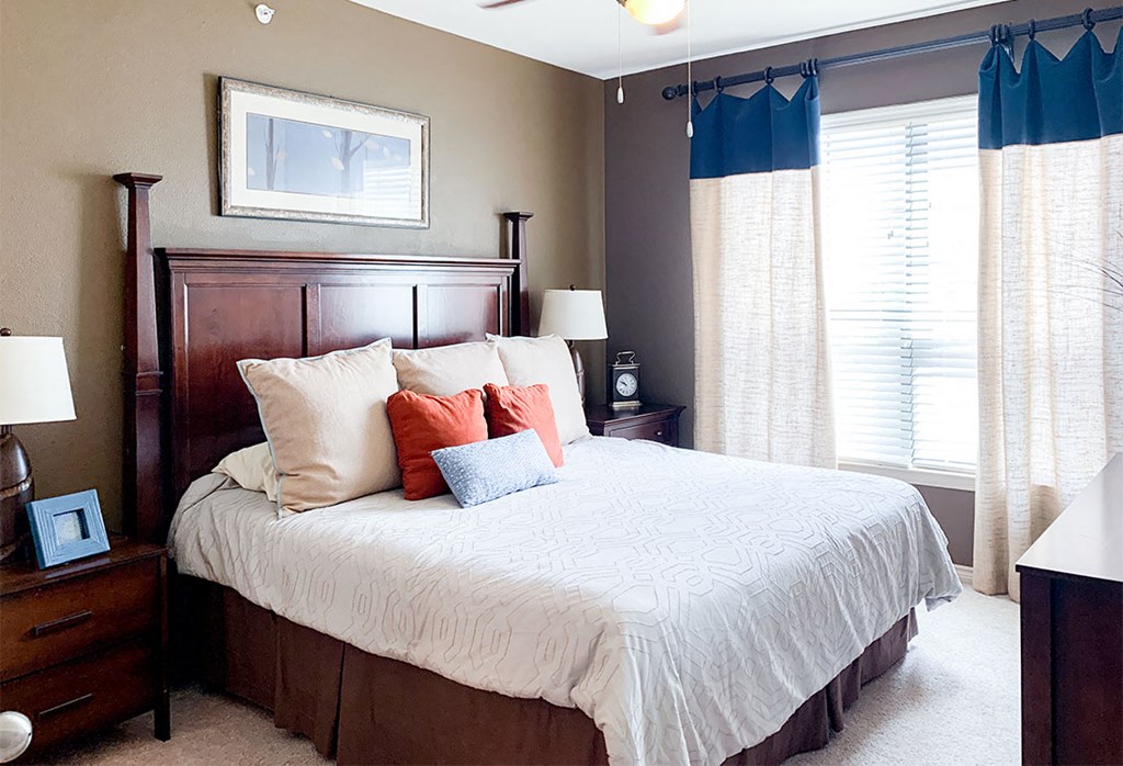 a bedroom with a large bed and two windows