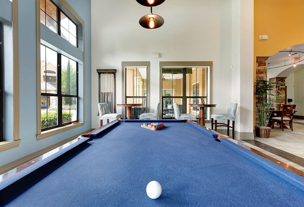 a pool table in a living room with a window