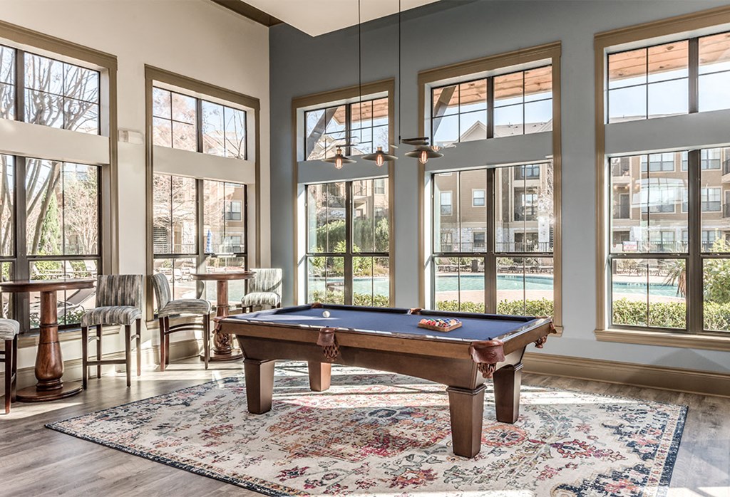 a pool table in a living room with windows