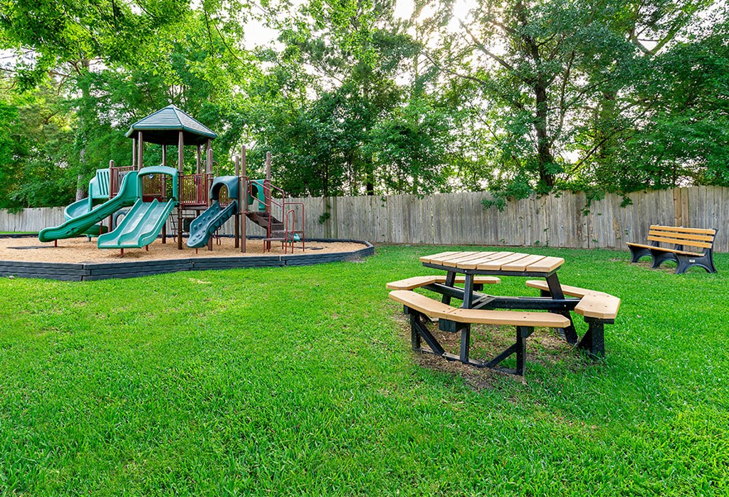 a playground with a picnic table and a swing set